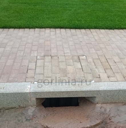 Установленный на дорожке уличный люк Драго, вымощенный брусчаткой в раскладку покрытия